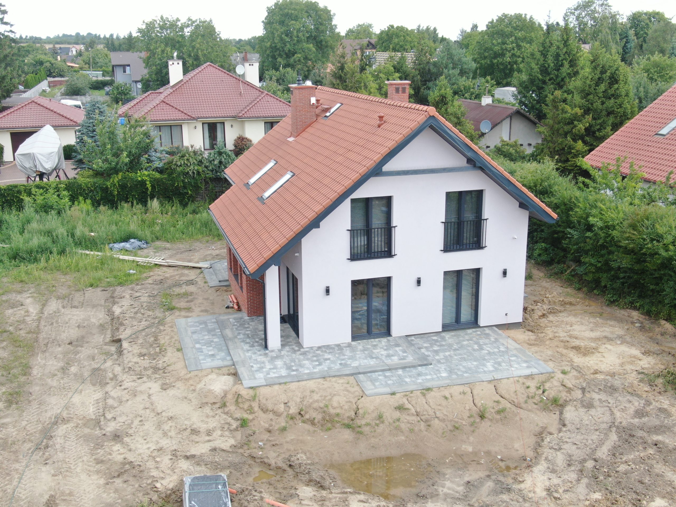 Biały budynek mieszkalny z czerwoną dachówką w Gdańsku, widok z drona
